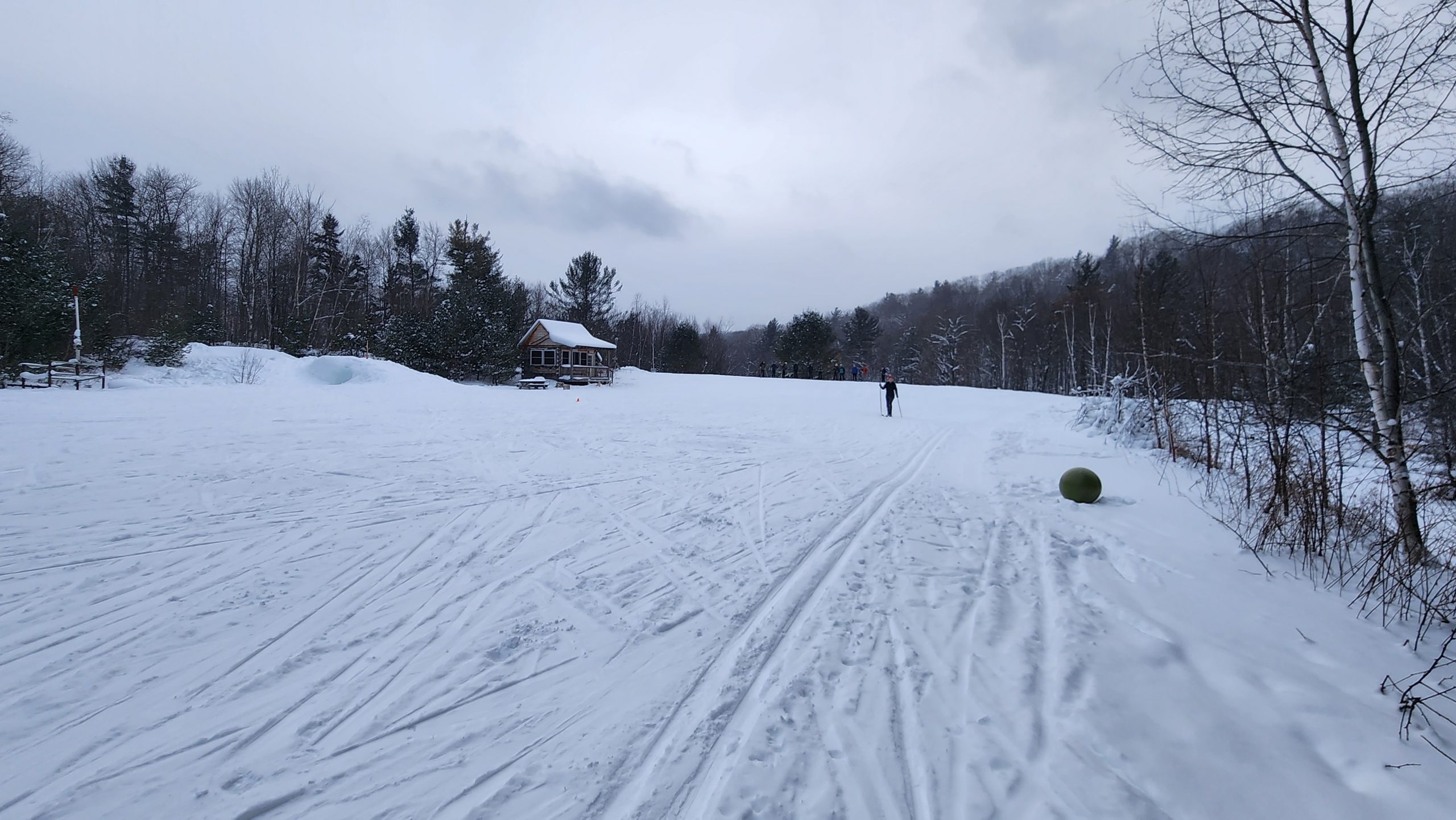 Full moon ski day, a skier skis an open meadow.