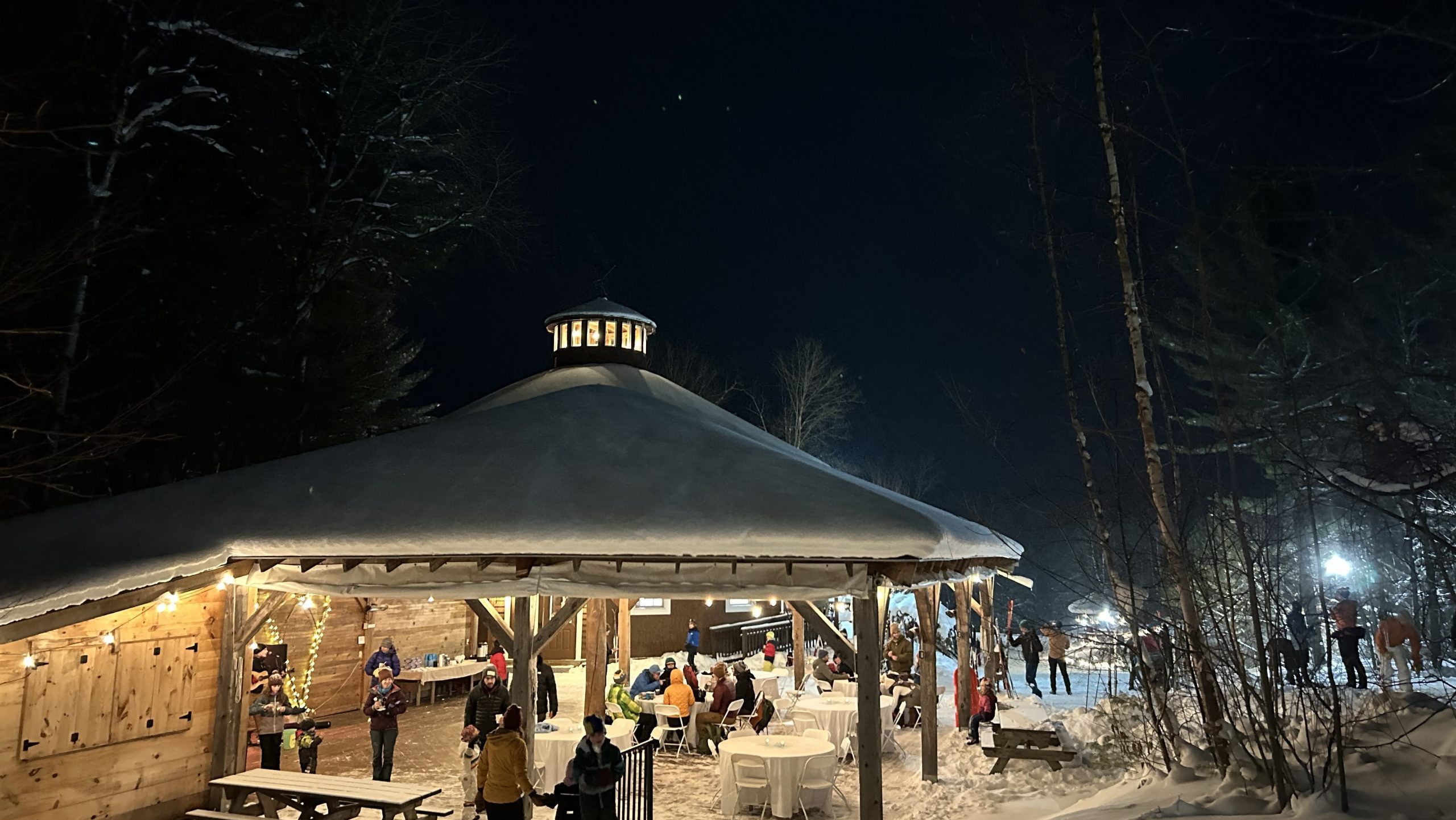 Skiers underneath the pavilion at night.